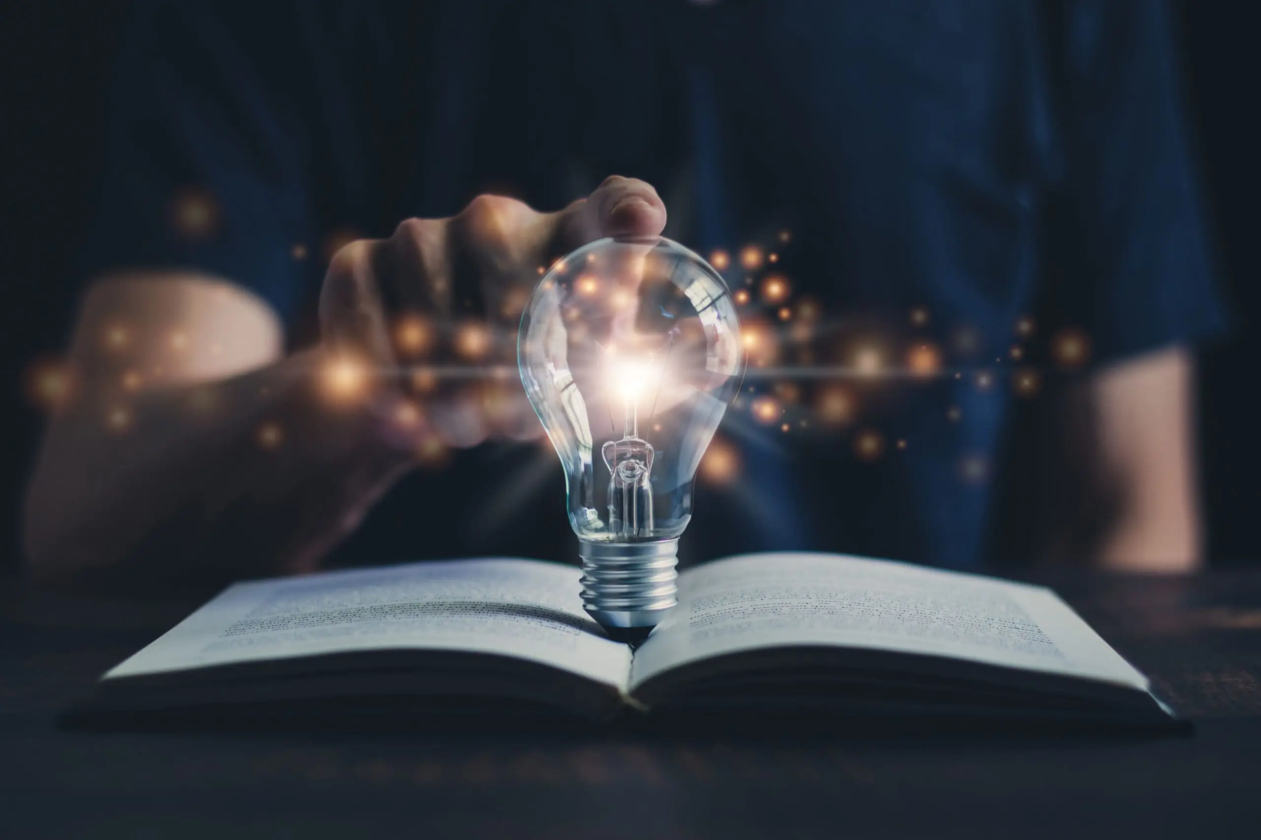 Glowing light bulb and book with glowing sparks to symbolize idea of instructional design and e-learning.