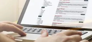A person using a laptop to scan job postings with salary info
