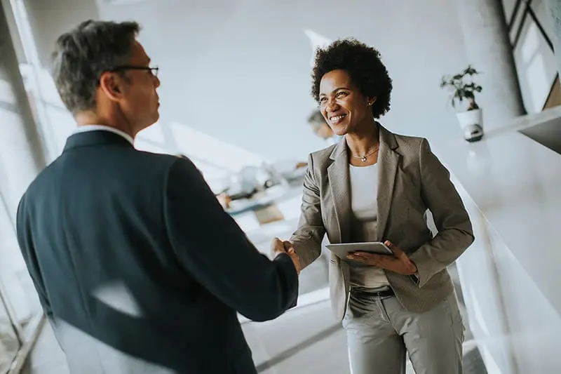 how-our-grads-advance A working professional shaking hands during an interview, showcasing career growth outcomes